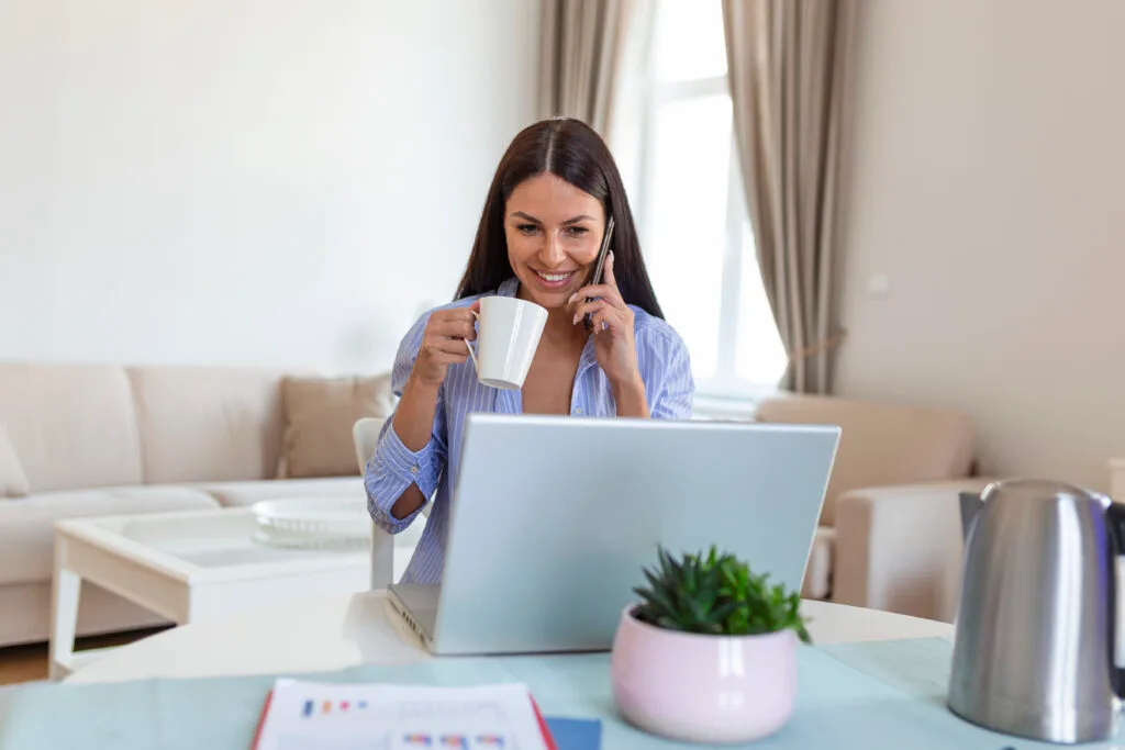 self-employed-woman-working-with-her-phone-laptop-home-with-cup-coffee-happy-woman-using-mobile-phone-while-working-home-with-laptop-smiling-woman-messaging-with-smartphone-1024x683 (1)